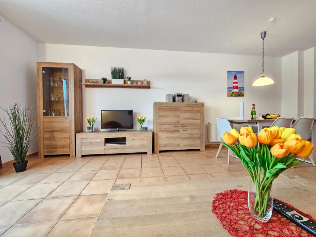 una sala de estar con un jarrón de tulipanes amarillos en Ferienhaus Baltrumkieker Mitte en Neßmersiel