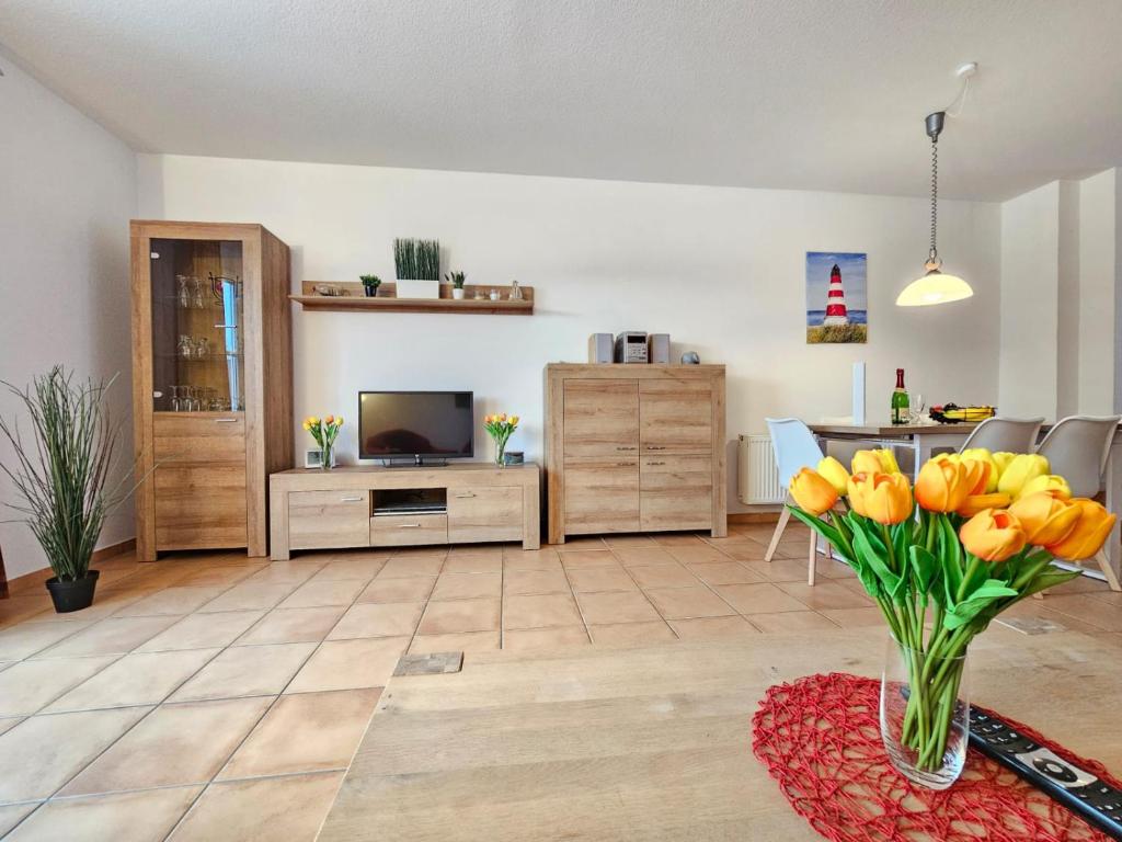 a living room with a vase of yellow tulips at Ferienhaus Baltrumkieker Mitte in Neßmersiel
