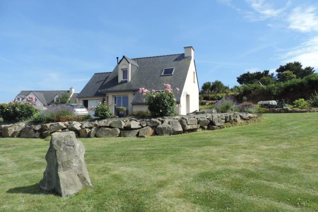 uma casa com uma pedra no meio de um campo em Maison 6 personnes vue mer em Plougrescant