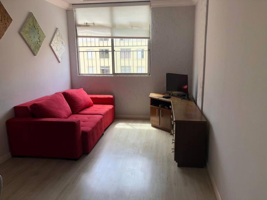 a living room with a red couch and a desk at Apartamento completo, com excelente localização in Americana