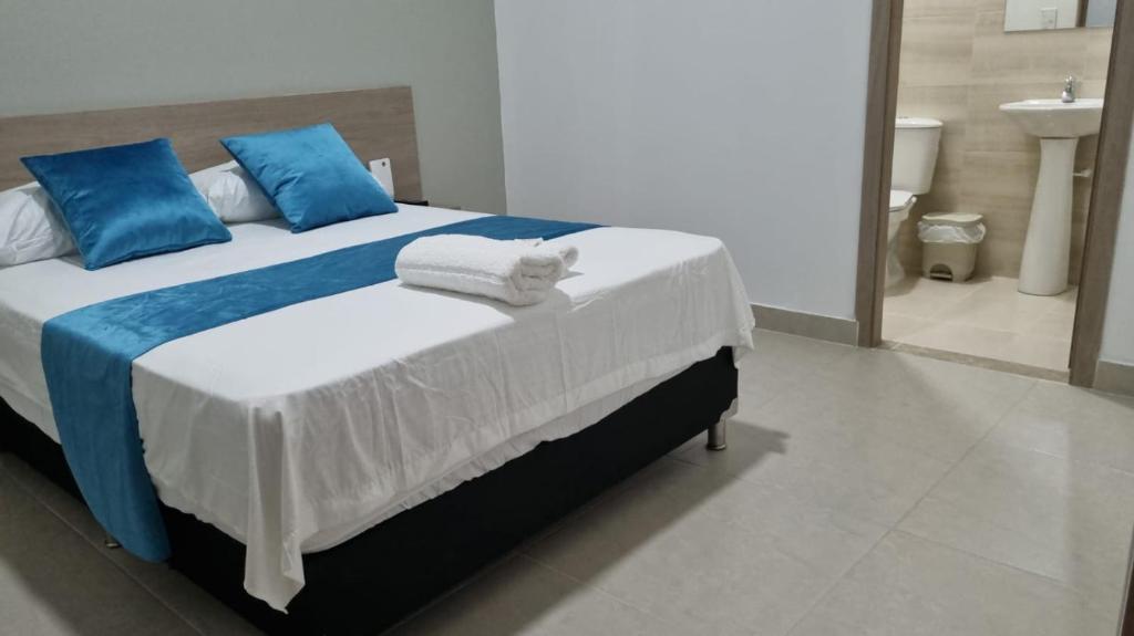 1 dormitorio con 1 cama grande con almohadas azules y blancas en Hotel Mirador Gastro Bar en Chinú