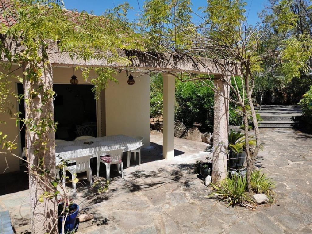 une pergola avec une table et un banc dans une cour dans l'établissement Villa San Antonu, Santa Giulia, à Porto-Vecchio