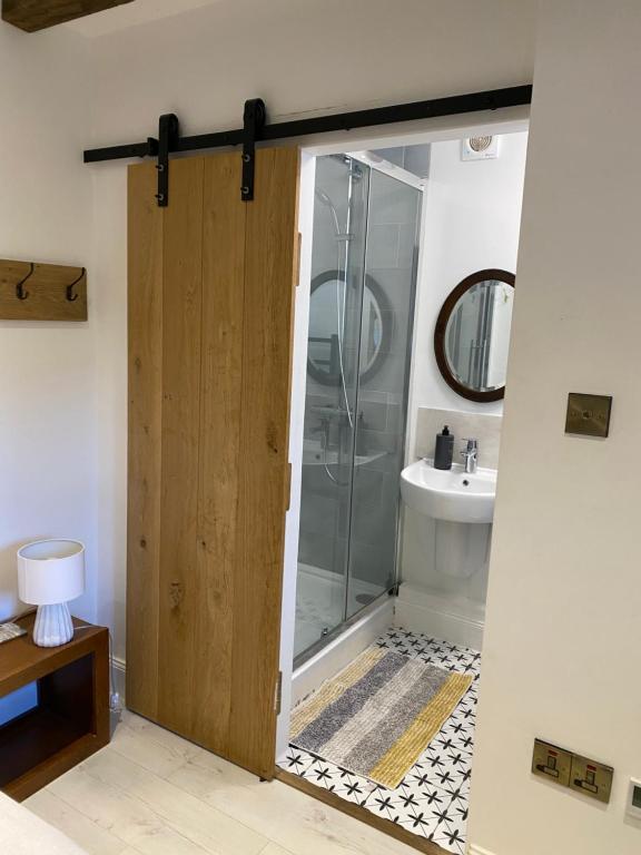 a bathroom with a shower and a glass door at Priory Cottage Stables in Cowden