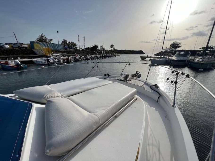 a white boat in the water with other boats at Bateau double cabine proche de la plage in Gourbeyre