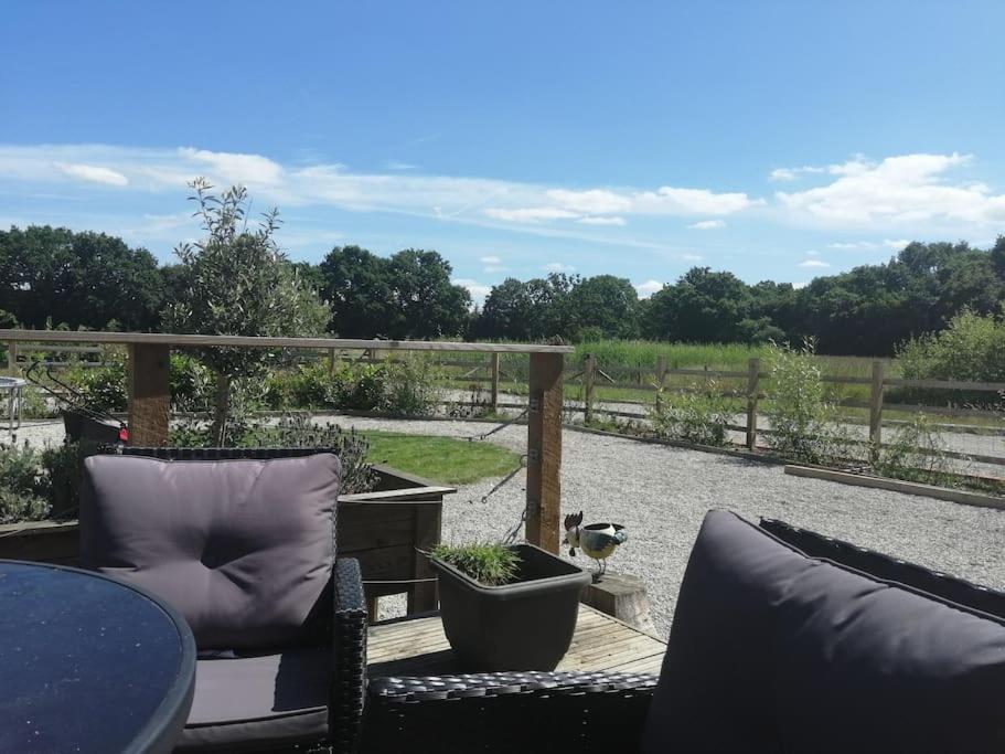 a patio with chairs and a table and a fence at Lillibelles lodge,Oak tree farm in Ashford