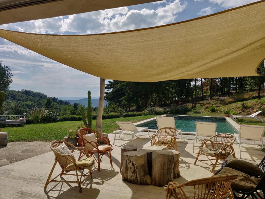 a patio with chairs and a table with a large umbrella at La Clairière de l'Ange Havre de paix en Drôme des Collines in Peyrins