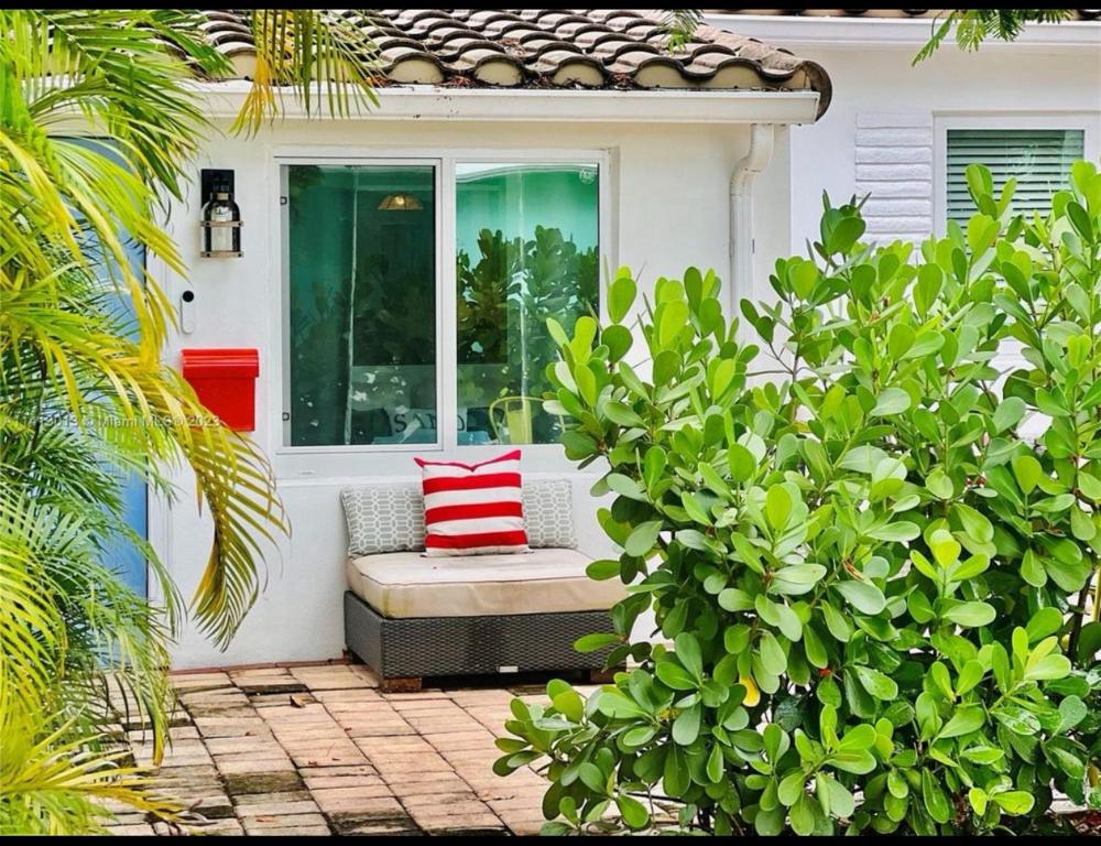 porche con banco y almohada roja y blanca en Private Fort Lauderdale cottage, en Fort Lauderdale