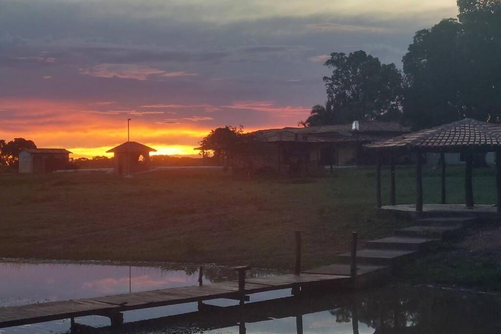 einen Sonnenuntergang über einem Feld mit einem Dock und einem Gebäude in der Unterkunft Casa de campo Sede de Fazenda - MT in Nossa Senhora do Livramento