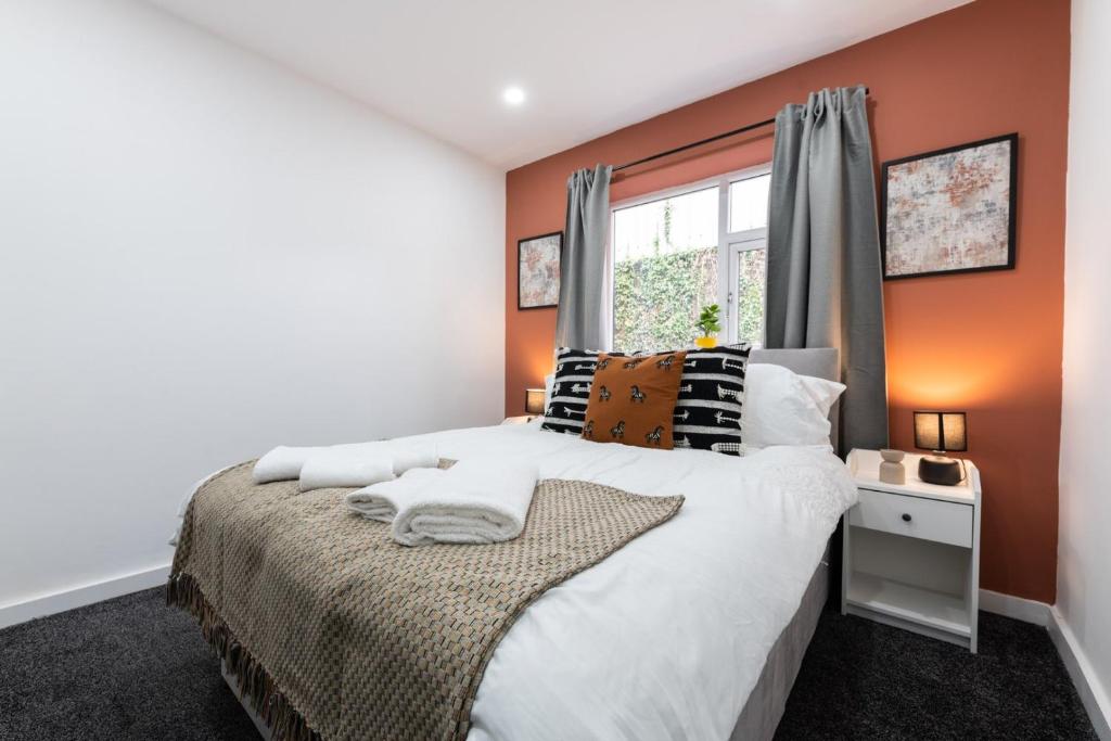 a bedroom with a large bed with orange walls at WiFi | Garden | 2BR in Cardiff