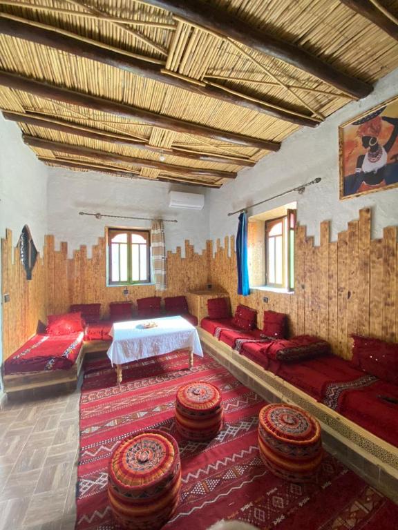 a room with a bed and some chairs and a rug at Casa Mona in Merzouga