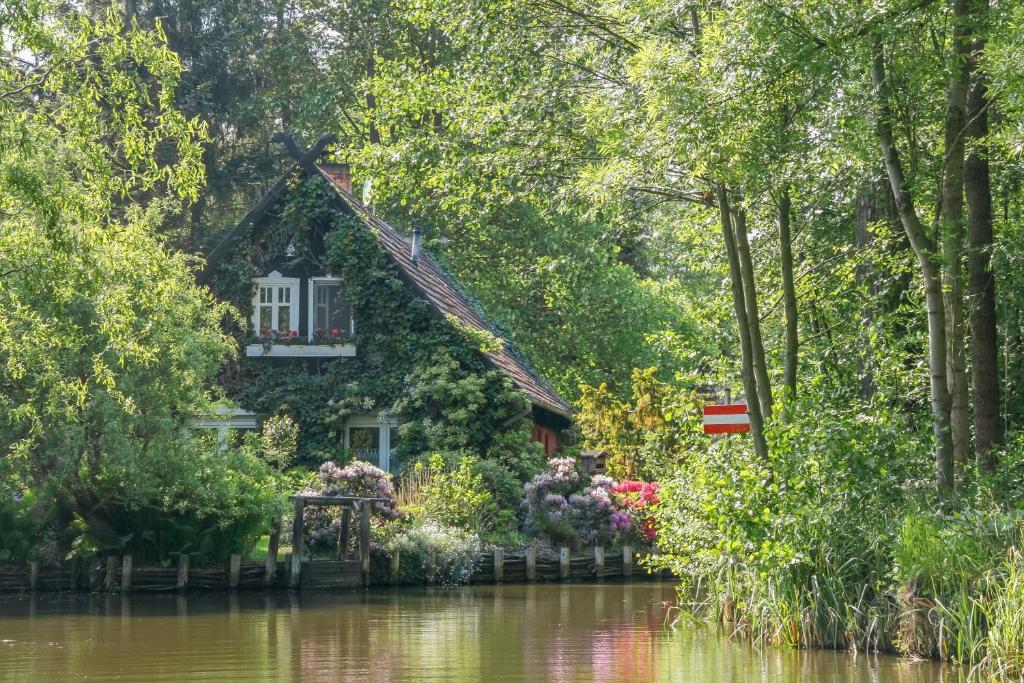 een huis aan de rivier met bomen en bloemen bij Spreewald Fewo direkt am Wasser in Lübbenau