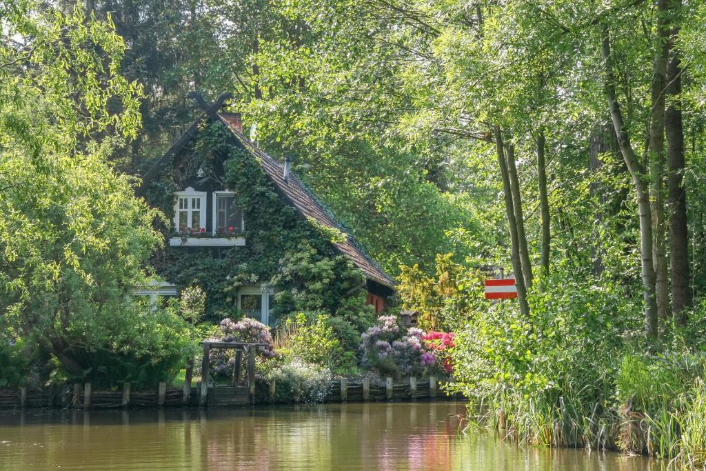 a house on the river with trees and flowers at Spreewald Fewo direkt am Wasser in Lübbenau