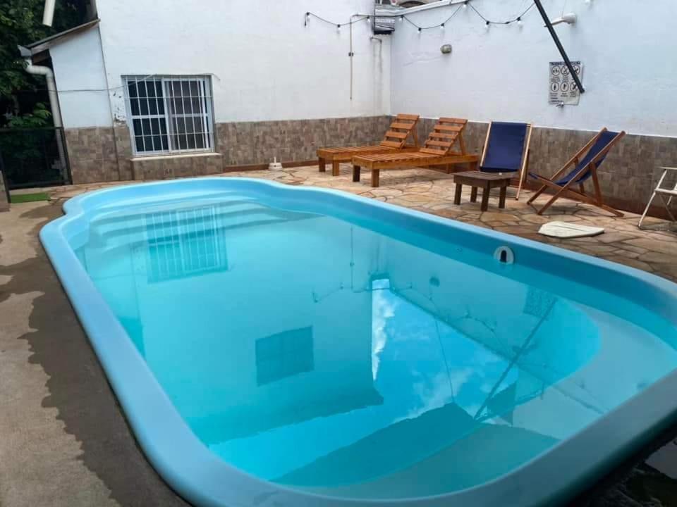 een blauw zwembad met 2 stoelen en een bank bij Rosas287 in Puerto Iguazú