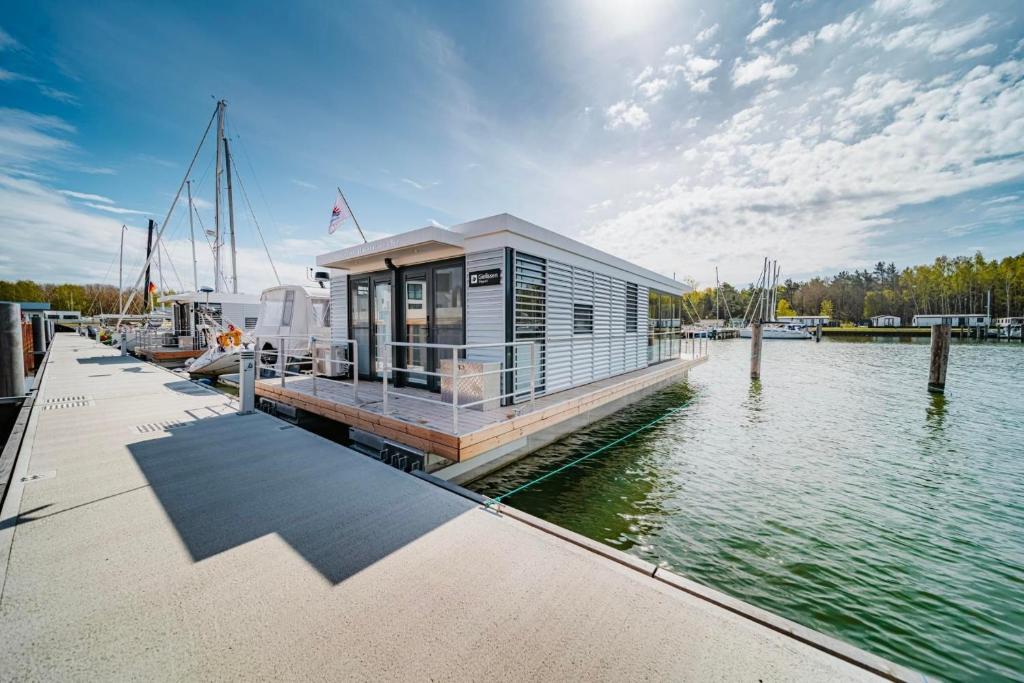 a small house on a dock on a body of water at Hausboot Trinity - LP5 in Peenemünde