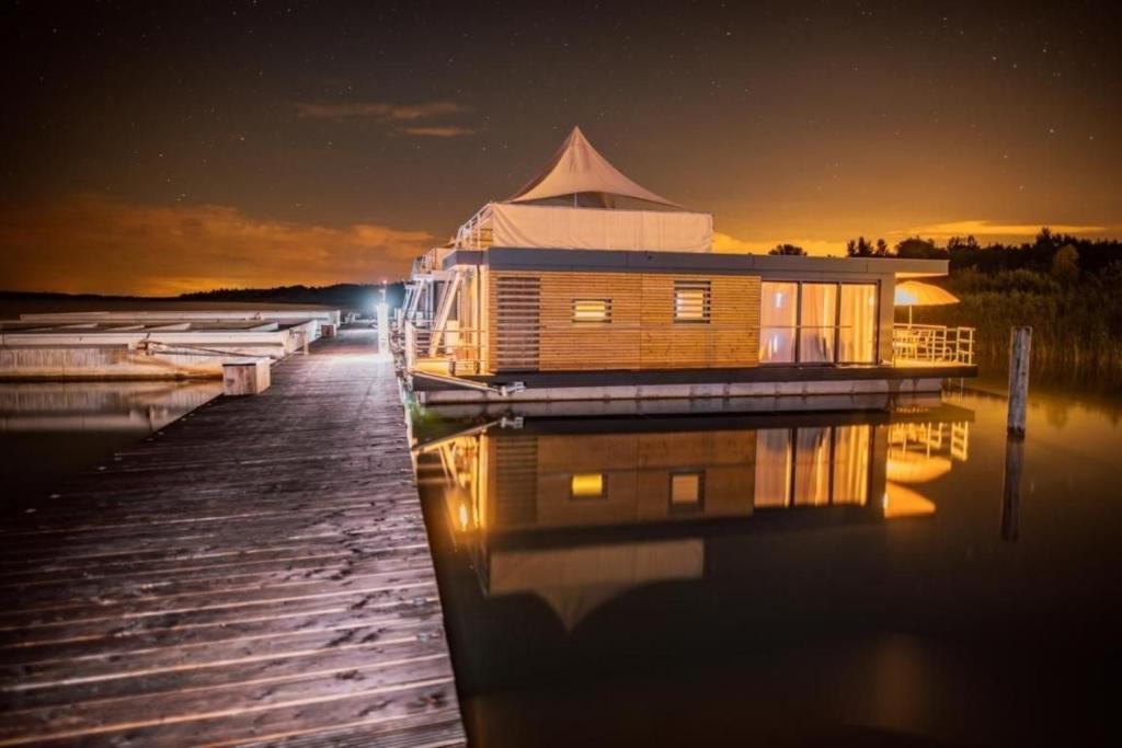 a house on a dock on the water at night at Hausboot Bellini in Klitten
