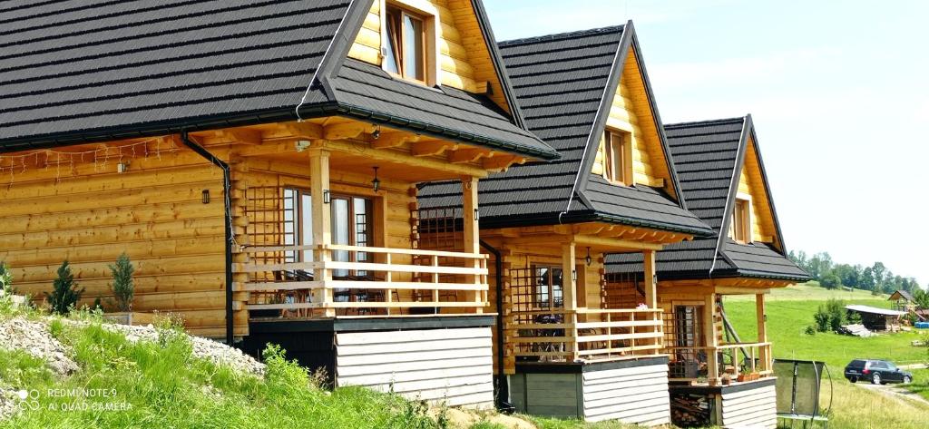 a log cabin with a black roof at Domki Trzy Tatry in Ząb