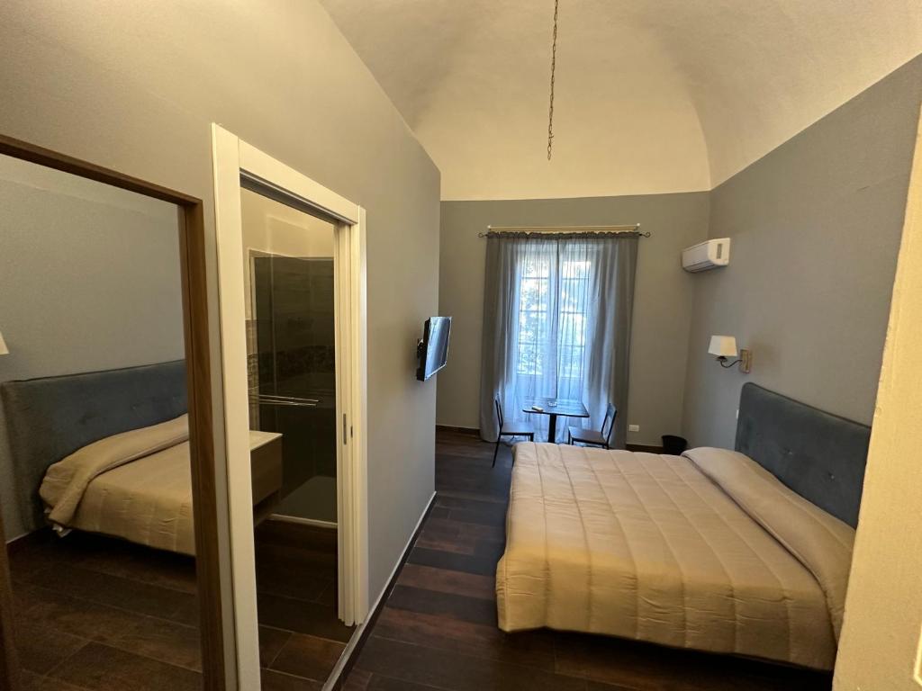 1 dormitorio con 2 camas y espejo en B&B Palazzo Fischetti en Catania