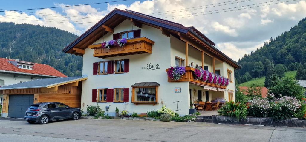 une maison avec des boîtes de fleurs sur son côté dans l'établissement Haus Luise, à Bad Hindelang