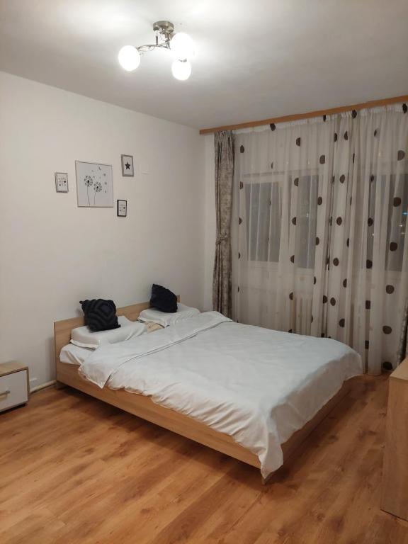 una camera da letto con letto, lenzuola bianche e pavimenti in legno di Mari a Focşani