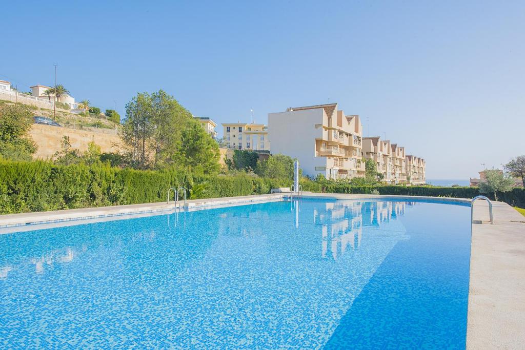 una gran piscina azul con edificios en el fondo en Apartamento Zeus - PlusHolidays, en Calpe