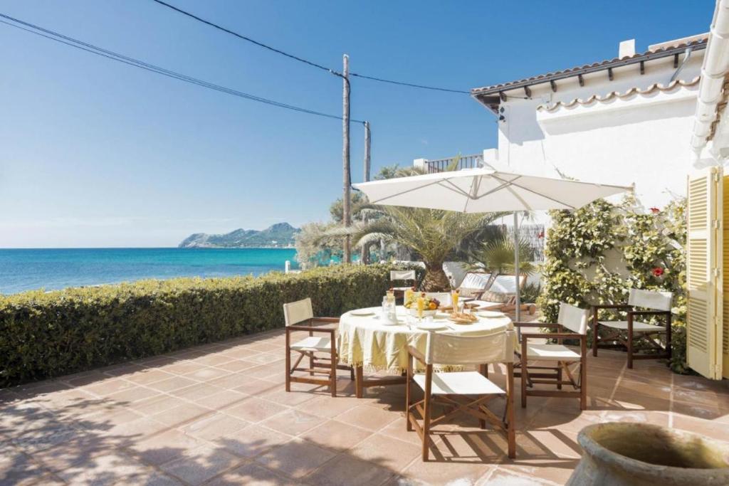 una mesa y sillas con sombrilla y el océano en Casa Morant On The Promenade Mhm en Cala Ratjada