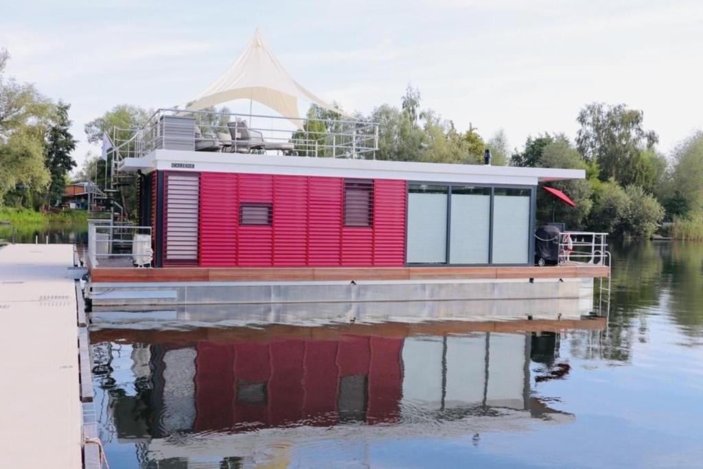 a red house on a dock on a body of water at Hausboot CALIENE - LP9 in Höxter