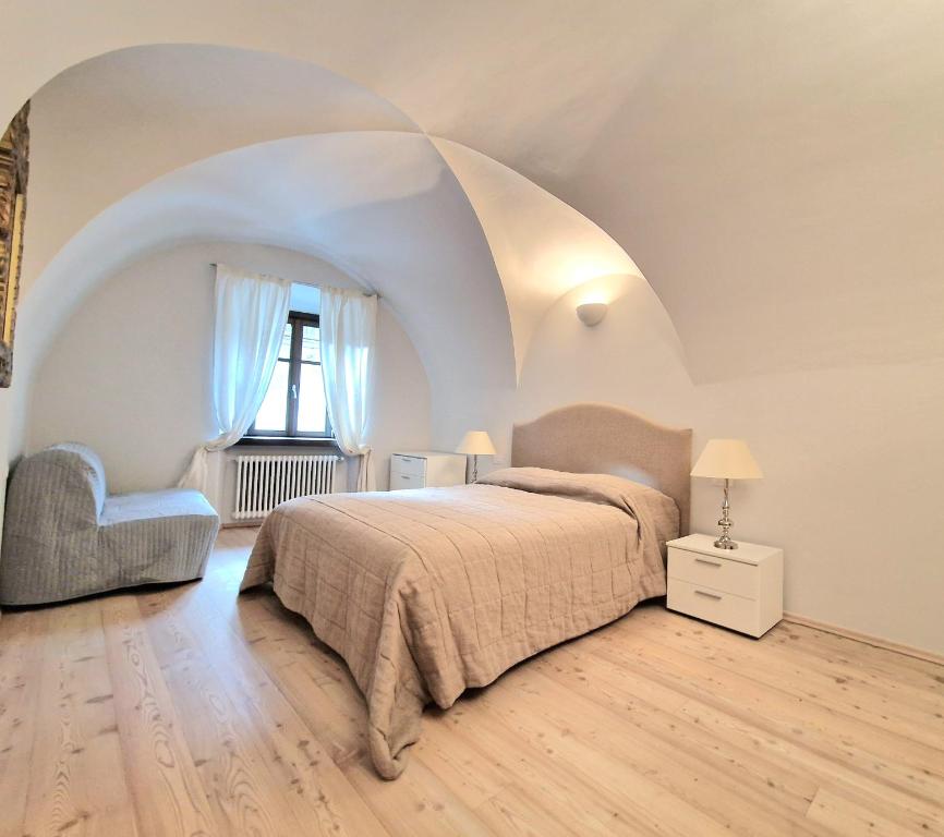 a bedroom with a bed and a chair and a window at Sartori Mountain Apartment in Pinzolo