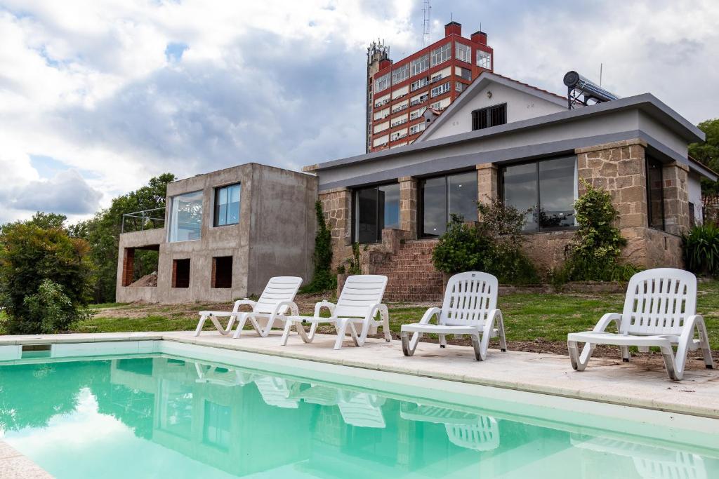 un grupo de sillas sentadas junto a una piscina en Casa de Campo con vista al lago! Villa del Lago - Villa Carlos Paz en Villa Carlos Paz