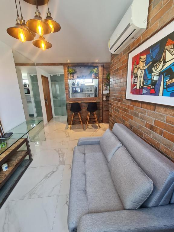 a living room with a couch and a brick wall at Apartamento em boa viagem in Recife