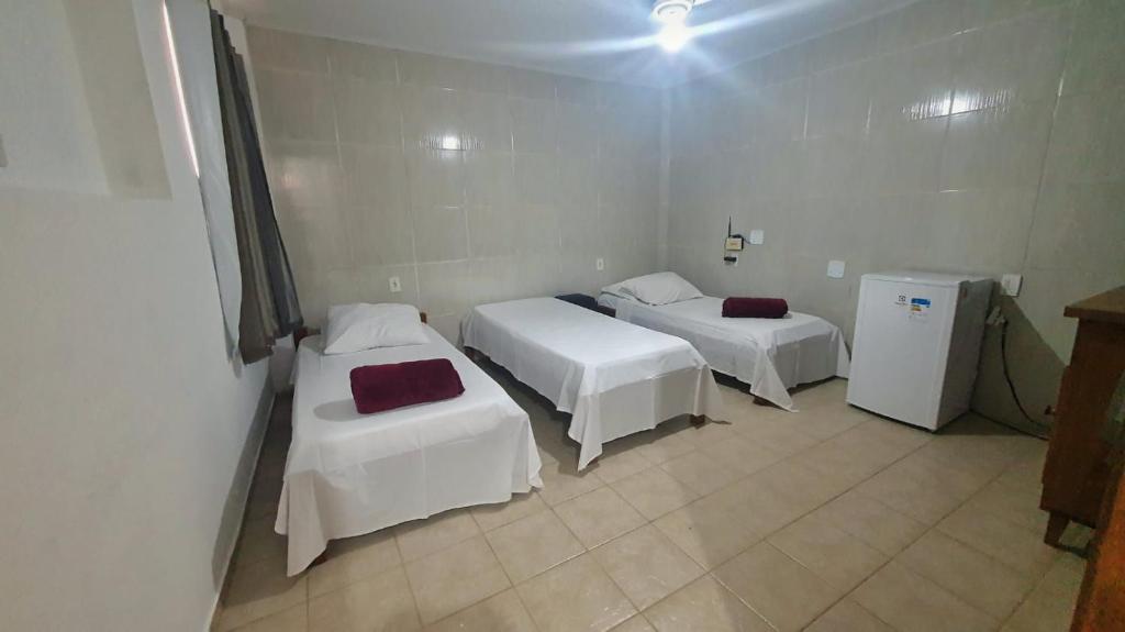 a room with two beds and a refrigerator at Suíte Centro in São João Batista do Glória