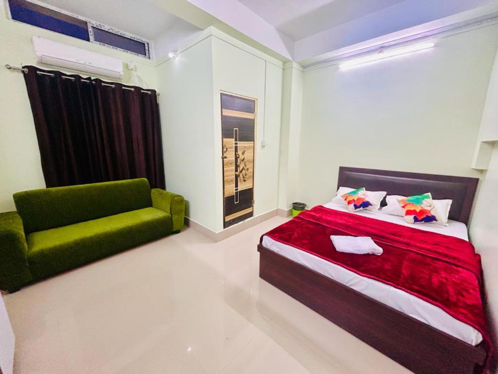 a bedroom with a bed and a green chair at JM Suites in Tezpur