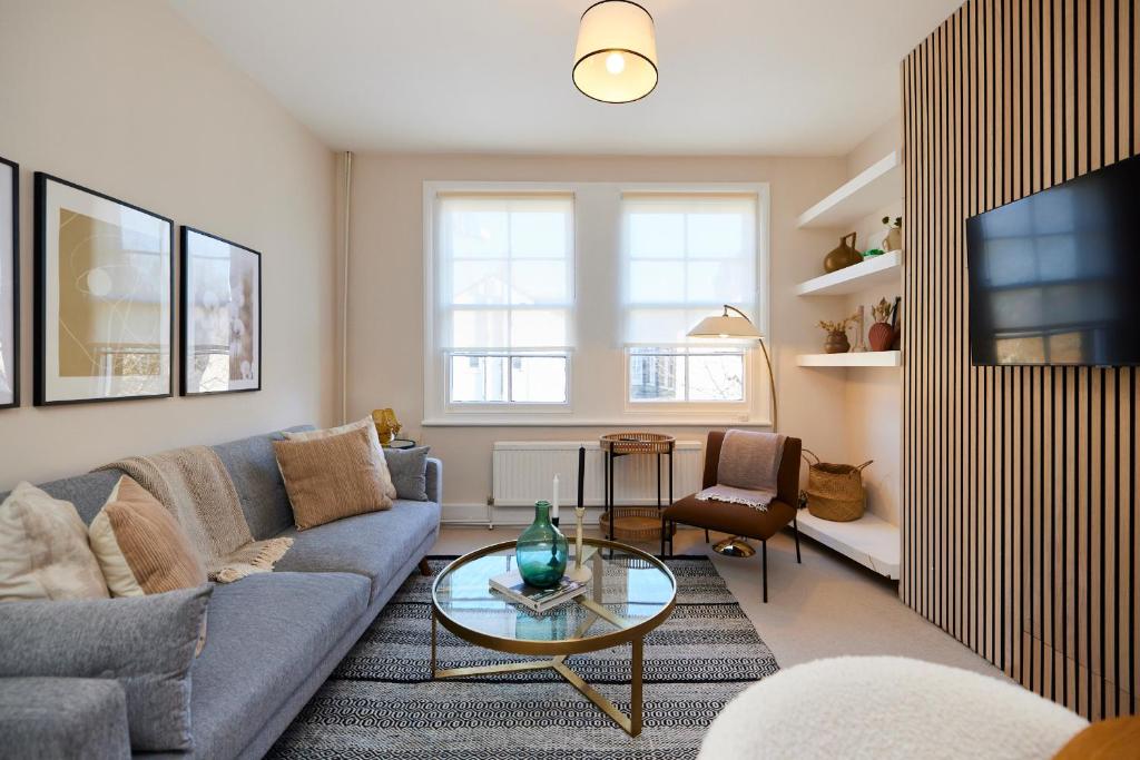 un soggiorno con divano e tavolo di The Elmington Estate Place - Elegant 1BDR Flat a Londra