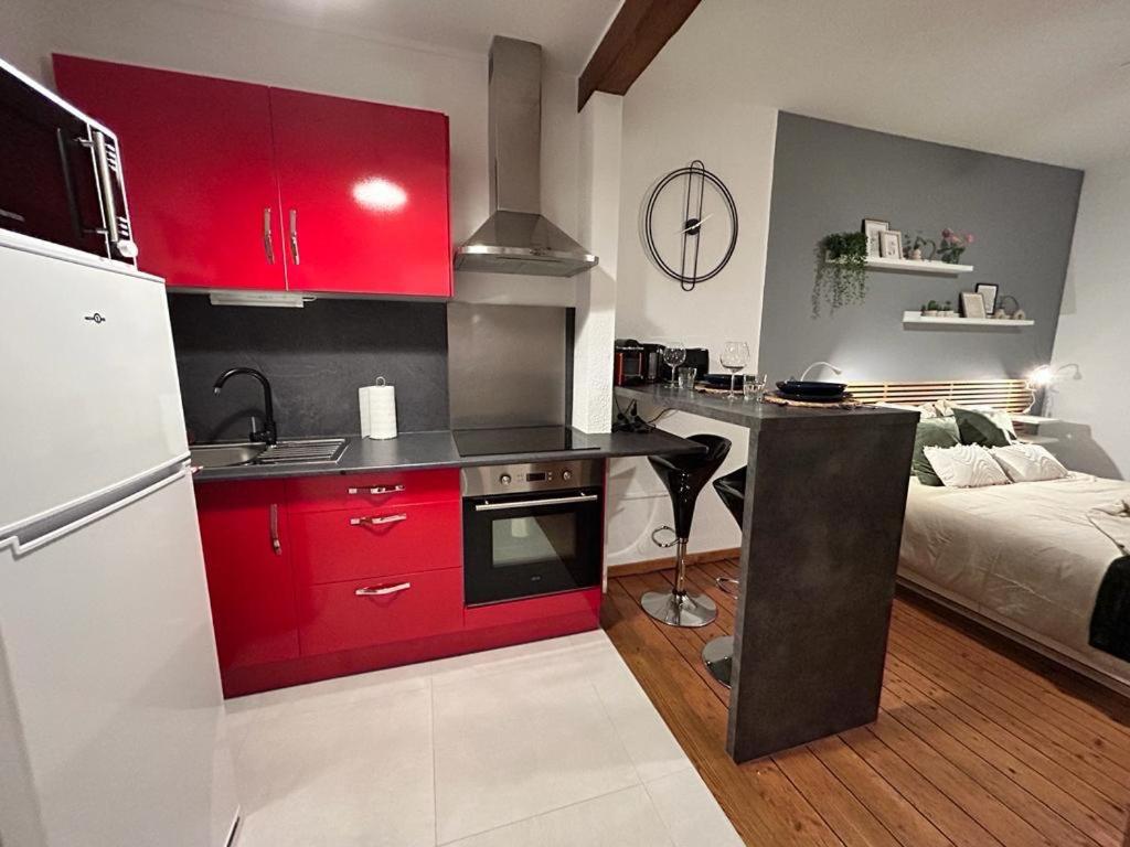 een keuken met rode kasten en een bed in een kamer bij Chez Michèle et Philippe in Munster