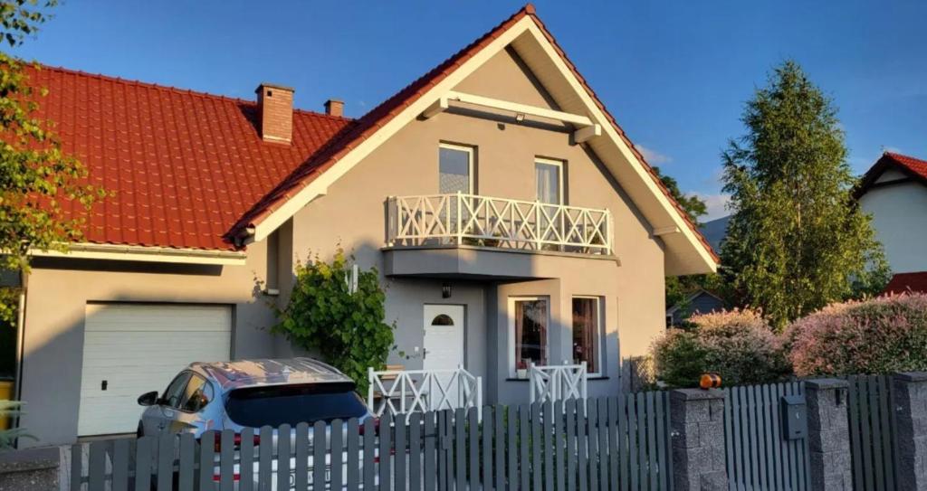 una casa blanca con una valla y un coche en Teraz Karpacz, en Karpacz