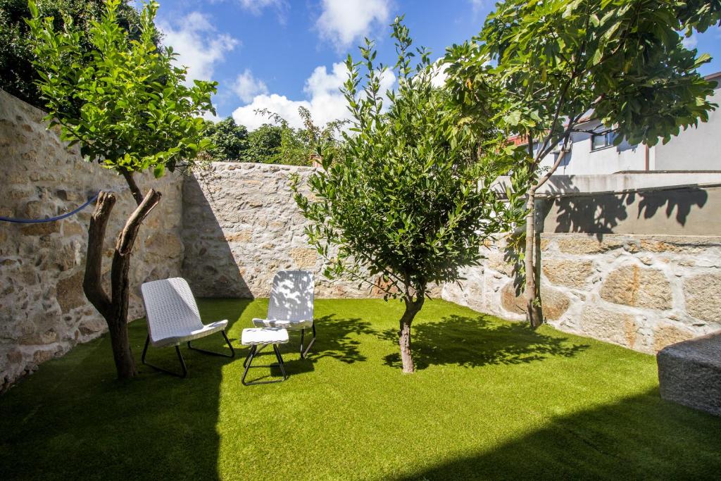 un jardín con una silla y dos árboles. en Guest H4U - Heroismo, en Oporto
