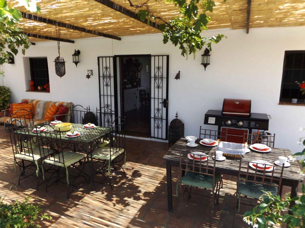 eine Terrasse mit Tischen, Stühlen und einem Sofa in der Unterkunft Casa Almendros in Sedella