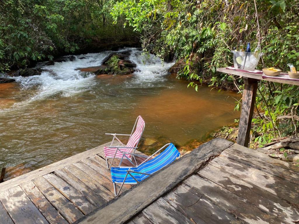 two chairs sitting on a wooden deck next to a river at Casa Saracura in Aguaçu