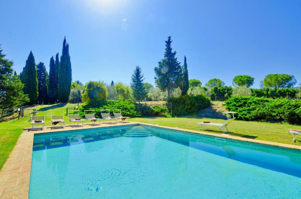 una piscina en un patio con sillas y árboles en Villa Piandisette, en Cetona