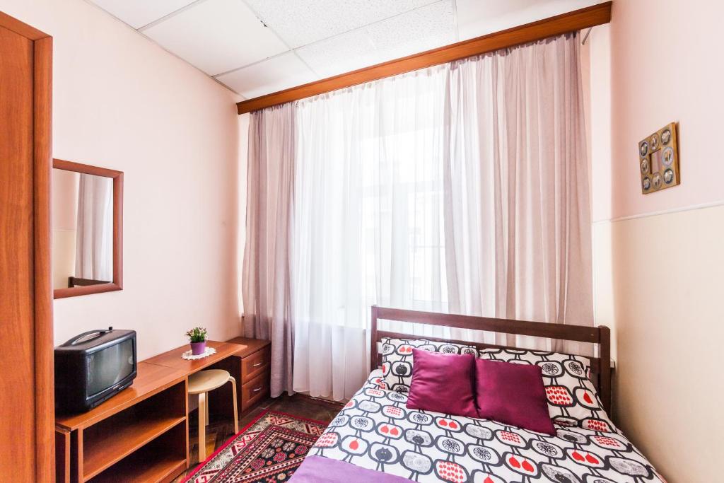 a hotel room with a bed and a desk and a television at WonderHostel on Nevsky 23 in Saint Petersburg
