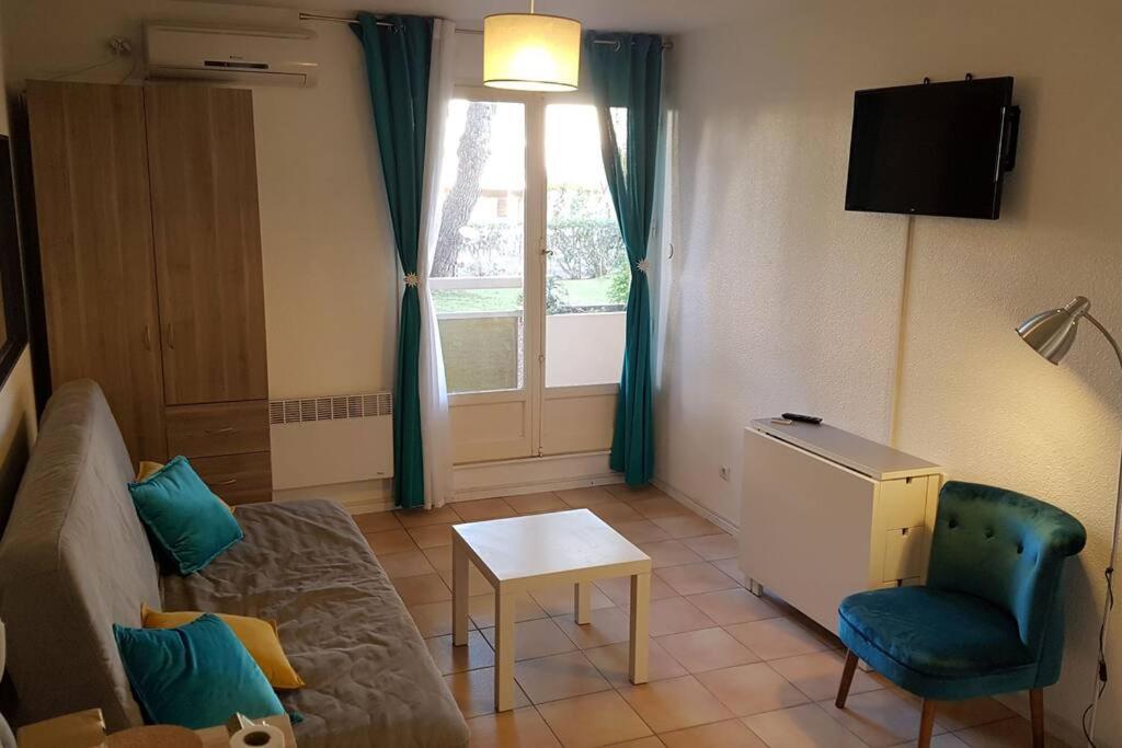 - un salon avec un canapé, une chaise et une fenêtre dans l'établissement Studio rez-jardin proche plage WiFi, clim, garage, à Bormes-les-Mimosas