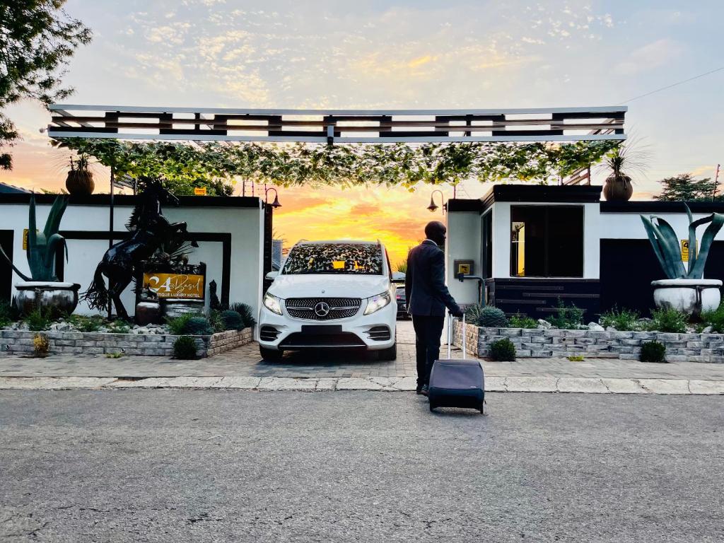 a man with a suitcase standing in front of a car at 24 On Basil Boutique Luxury hotel in Johannesburg