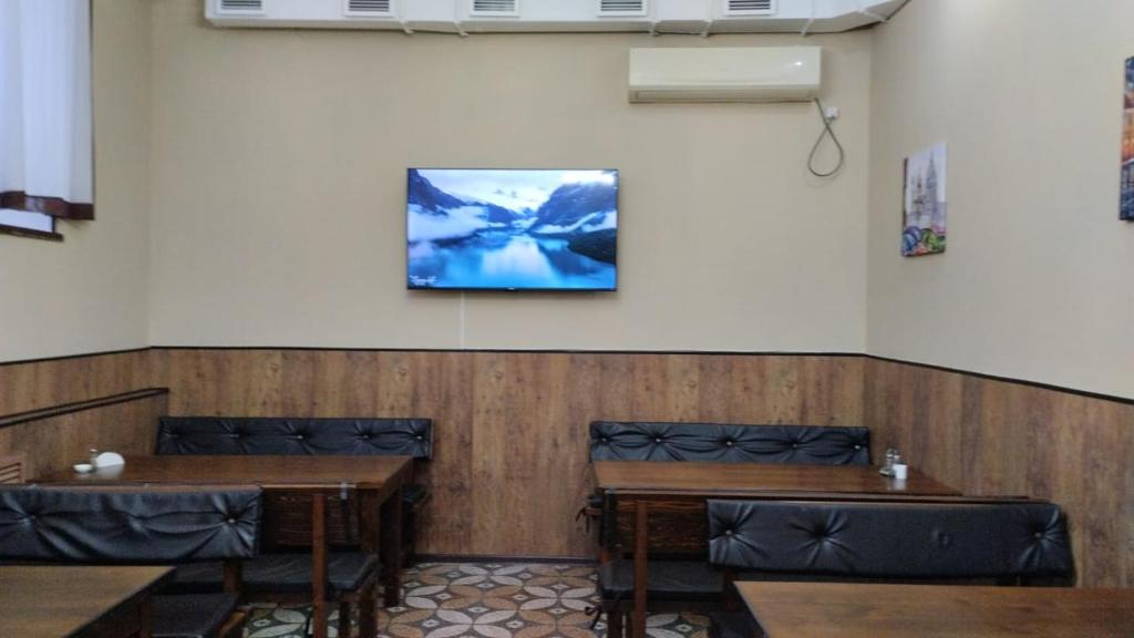 Ак-Тай Гостиный Двор في أوست - كامينوغورسك: غرفة بها طاولتين وتلفزيون على الحائط