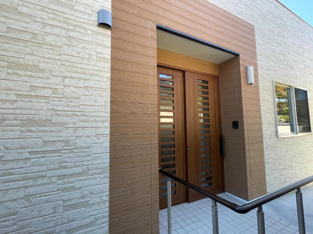 een houten deur aan de zijkant van een gebouw bij Glocal Kasugai Onsen - Vacation STAY 64477v in Fuefuki