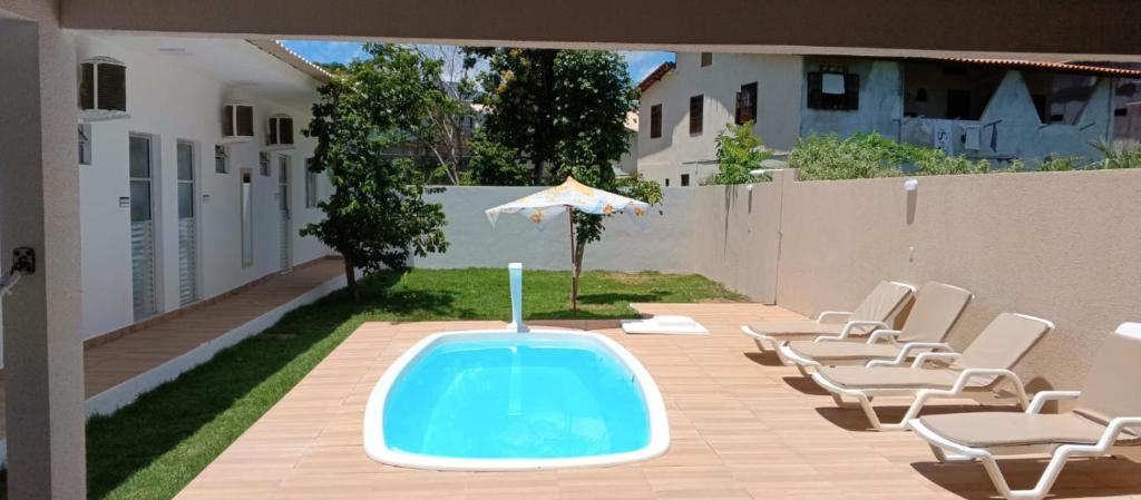 uma piscina com cadeiras e um guarda-sol num quintal em Suítes com piscina Praia do Forte Tomas na Praia do Forte