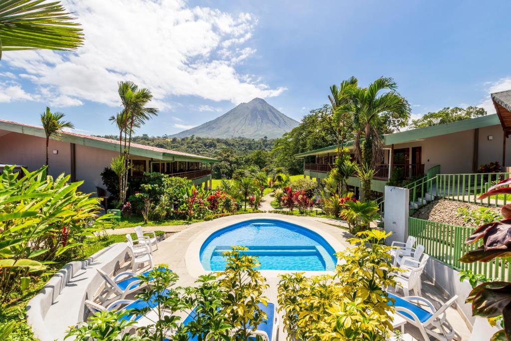 un complejo con piscina y montaña de fondo en Hotel Lavas Tacotal, en Fortuna