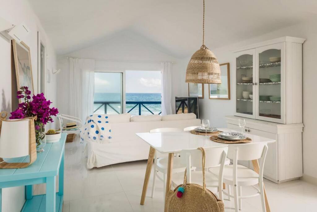 ein weißes Wohnzimmer mit einem Tisch und einer Couch in der Unterkunft Casa Charcón Alto, en primera línea de mar - Best Villas Lanzarote in Famara