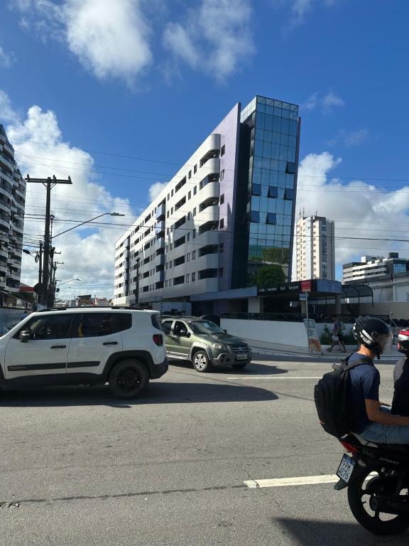 a man riding a motorcycle on a city street with cars at NEO 1.0 in Maceió