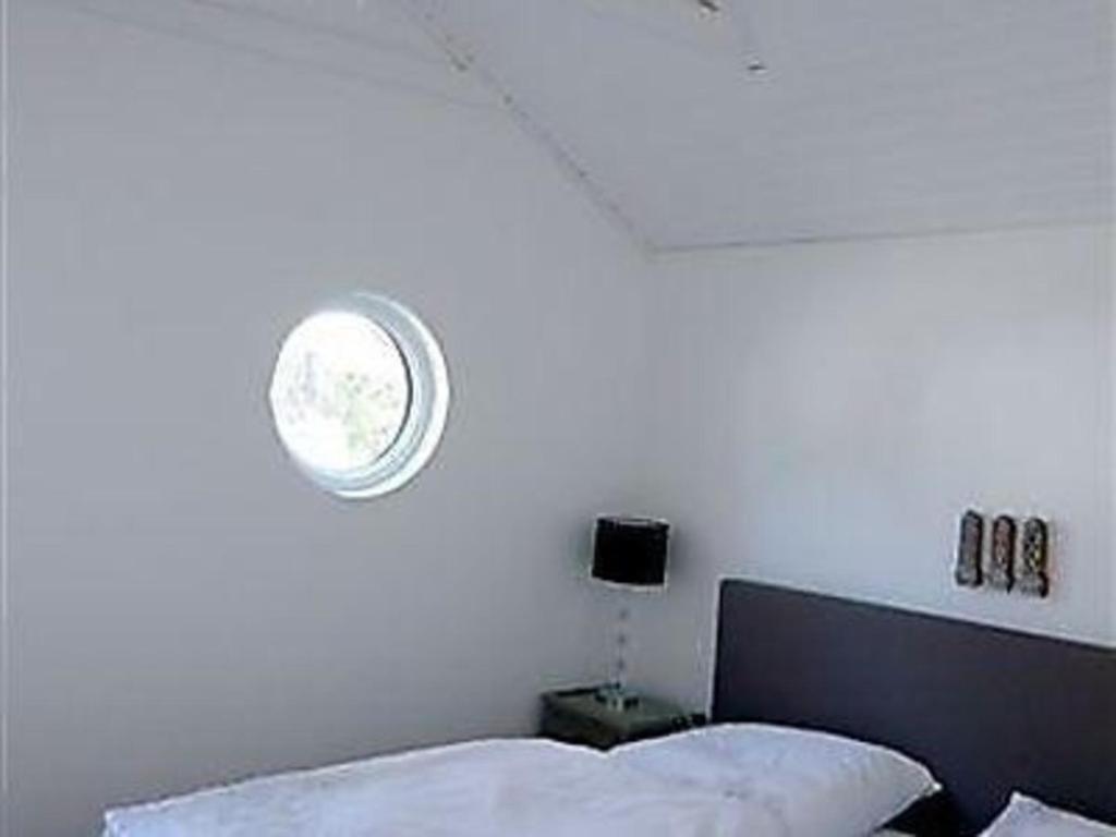 - une chambre dotée d'un mur blanc avec une horloge au-dessus d'un lit dans l'établissement Schönes Ferienhaus in Mönsterås mit Garten, Terrasse und Grill, à Mönsterås