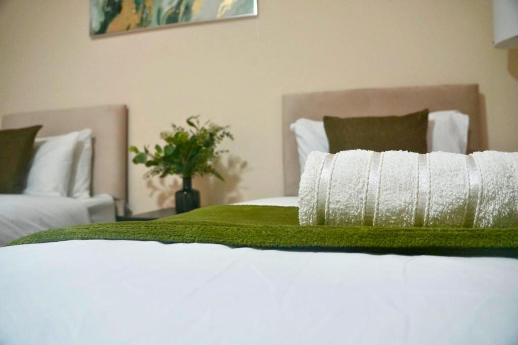 a white bed with a green blanket on it at Luxury Home near NEC, BHX with Parking and Netflix in Solihull