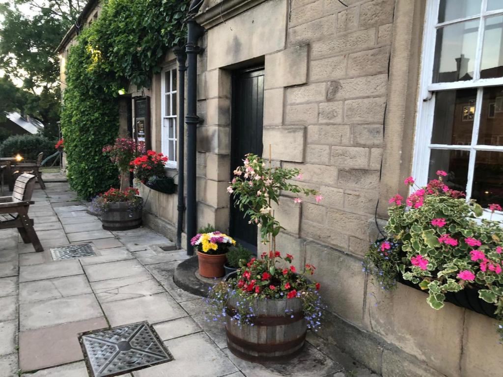 un edificio con macetas de flores delante de una puerta en The Tavern, en Matlock